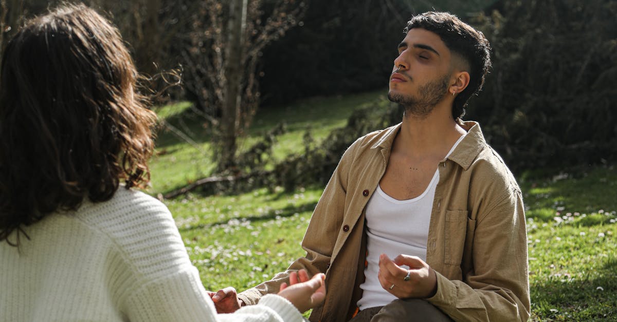 A peaceful moment of a couple meditating on grass in a serene outdoor location.
